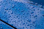 Raindrops on the hood of a blue car